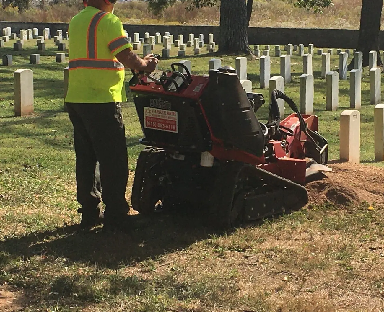 An operator running a stump grinder over a cut stump